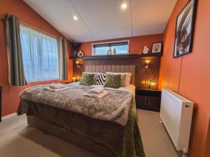 a bedroom with a large bed with orange walls at Honeysuckle Lodge in Bassenthwaite
