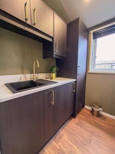 a kitchen with brown cabinets and a sink and a window at Honeysuckle Lodge in Bassenthwaite +15 photos