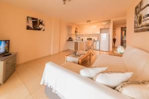 a living room with a white couch and a kitchen at A Home From Home in Palm-Mar