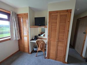 a room with a bedroom with a desk and a television at Peedie Sea Accommodation in Orkney