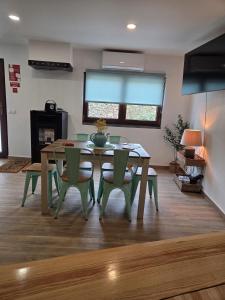 a dining room with a table and green chairs at Pátio do Tear in Sobreira Formosa