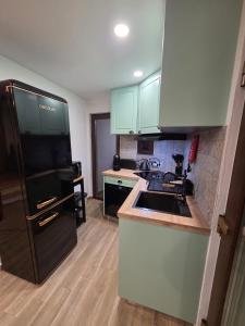 a kitchen with green cabinets and a black refrigerator at Pátio do Tear in Sobreira Formosa +3 photos
