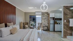 a bedroom with a white bed and a kitchen at DonDave Guesthouse in Rustenburg