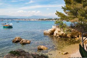 a body of water with rocks and a boat at Eden Cottages - Premium Cottage avec Piscine in Antibes