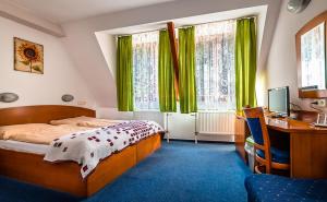 a bedroom with a bed and a desk and green curtains at Relax hotel FIM in Belá