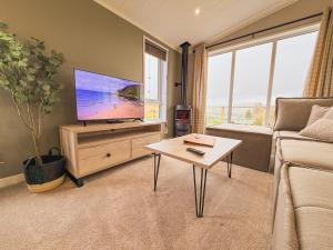 a living room with a flat screen tv and a table at Sycamore Lodge in Bassenthwaite