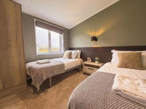 a bedroom with two beds and a window at Sycamore Lodge in Bassenthwaite