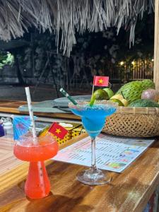 two cocktails on a table with a basket of fruit at Homestay JB Sơn Hải in Thôn Sơn Hải