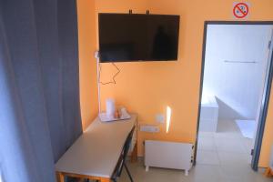 a room with a desk with a television on the wall at Bataung Guest House in Mafeteng +4 photos