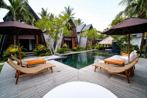 a resort with a swimming pool with chairs and umbrellas at Kies Villas Lombok in Kuta Lombok
