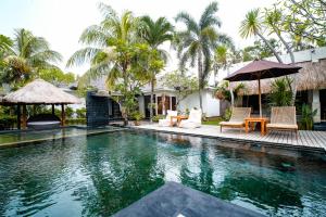 a swimming pool in a villa with palm trees at Kies Villas Lombok in Kuta Lombok