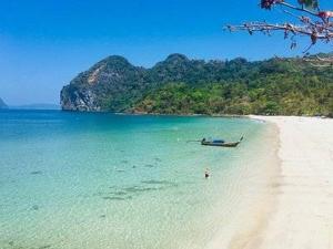 a beach with a boat in the water at Mook Phoopha Guest House in Ko Mook