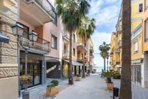 a street in a city with palm trees and buildings at Hostdomus - Salsedine Apartment in Alassio