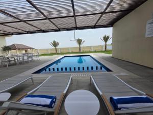 a swimming pool with chairs and a table and a building at Sada Villas in Barka