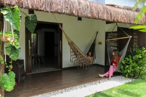 two girls sitting in hammocks on the porch of a house at Vila Loop in São Miguel do Gostoso