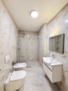 a white bathroom with a toilet and a sink at Hotel Apart Odeon in Durrës +92 photos