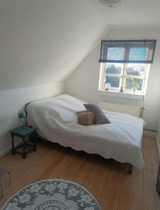 a bedroom with a bed with white sheets and a window at Skøn rolig villa in Dianalund