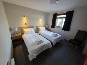 a bedroom with two beds and a chair and a window at Peedie Sea Accommodation in Orkney