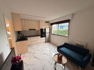 a living room with a blue couch and a kitchen at Studio neuf élégant- calme & cosy in Oyonnax