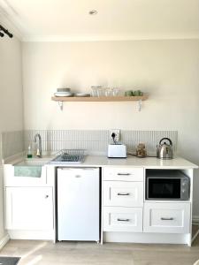 a kitchen with white cabinets and a microwave at Mountain View Studio Hermanus in Hermanus