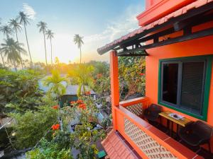 an orange house with a balcony with flowers and palm trees at Orange Villa Muine in Mui Ne
