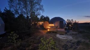 a tent and a bench in a field at night at Glamping Podniebny in Borsk