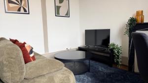 a living room with a couch and a table and a tv at Escapade sur la Loire in Nevers +7 photos