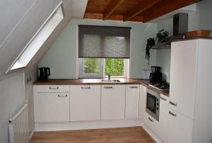 a kitchen with white cabinets and a sink and a window at Torenvalk I Genieten nabij Bos in Zwiggelte