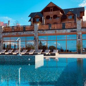 a building with a swimming pool and a house at Hotel Seidorf Luxury Wellness & Spa in Karpacz