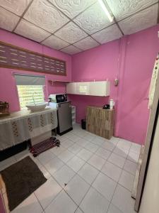a kitchen with pink walls and a white tile floor at Pink Hostel in Ko Tao