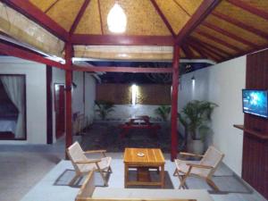 a living room with a table and chairs and a patio at Villa Kinagu in Gili Meno