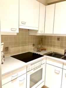 a kitchen with white cabinets and a sink at Sunshine centrum in Koksijde +7 photos