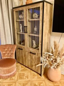 a wooden cabinet in a room with a chair and a vase at Sunshine centrum in Koksijde