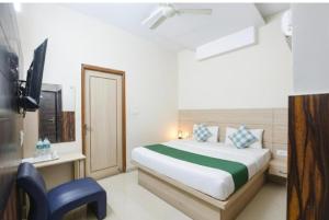 a bedroom with a bed and a chair and a television at Hotel Red ark inn in Mohali +7 photos