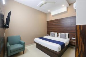 a bedroom with a bed and a blue chair at Hotel Red ark inn in Mohali