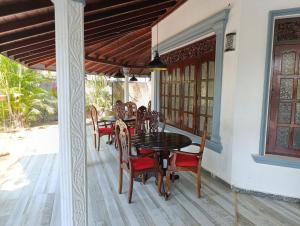 a dining room with a table and chairs on a porch at Zion Haven Villa in Tangalle