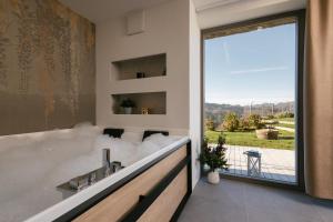a bathroom with a tub and a large window at Villa Diona in Loka pri Žusmu