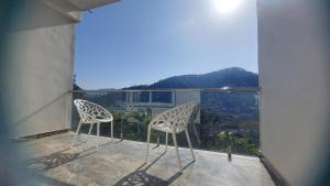 two chairs sitting on a balcony with a view at Nileshwar Home Stay in Bāgeshwar