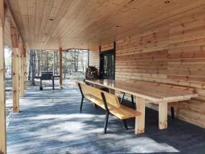a wooden cabin with a wooden table and a bench at Duży dom w lesie in Zatory