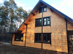 a log cabin with black windows in the woods at Duży dom w lesie in Zatory