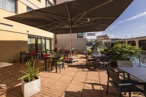un patio con tavoli, sedie e un ombrellone di Hôtel Terminus a Porrentruy