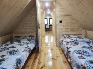 two beds in a room with wooden walls at Duży dom w lesie in Zatory