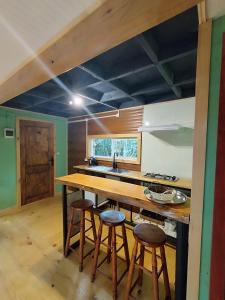 a kitchen with a wooden counter top and stools at Refugió Chaicura in Chonchi