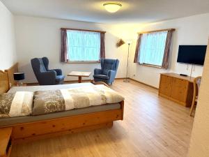 a bedroom with a bed and two chairs and a television at Hotel La Soglina in Soglio