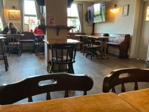 a restaurant with tables and chairs and a woman sitting at a table at Plough inn in Great Mongeham