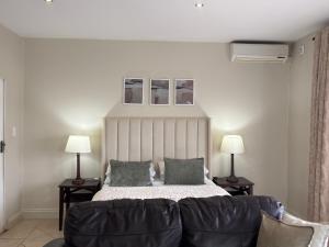 a bedroom with a bed with two lamps and a couch at The olive stay at Ocean view Villas F7 in Port Edward +34 photos