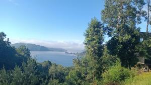 a view of a lake with a house and trees at El Estuario Niebla Cabin in Niebla +6 photos