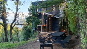 a house with a picnic table in front of it at El Estuario Niebla Cabin in Niebla