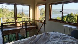 a bedroom with a bed and large windows with a view at El Estuario Niebla Cabin in Niebla
