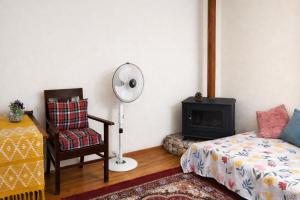 a bedroom with a bed and a chair and a fan at Peak & Pine cottage in Almora
